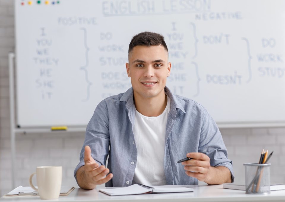 online-teacher-speaking-by-webcam-sitting-at-table-in-home-office-and-explaining-rules-english